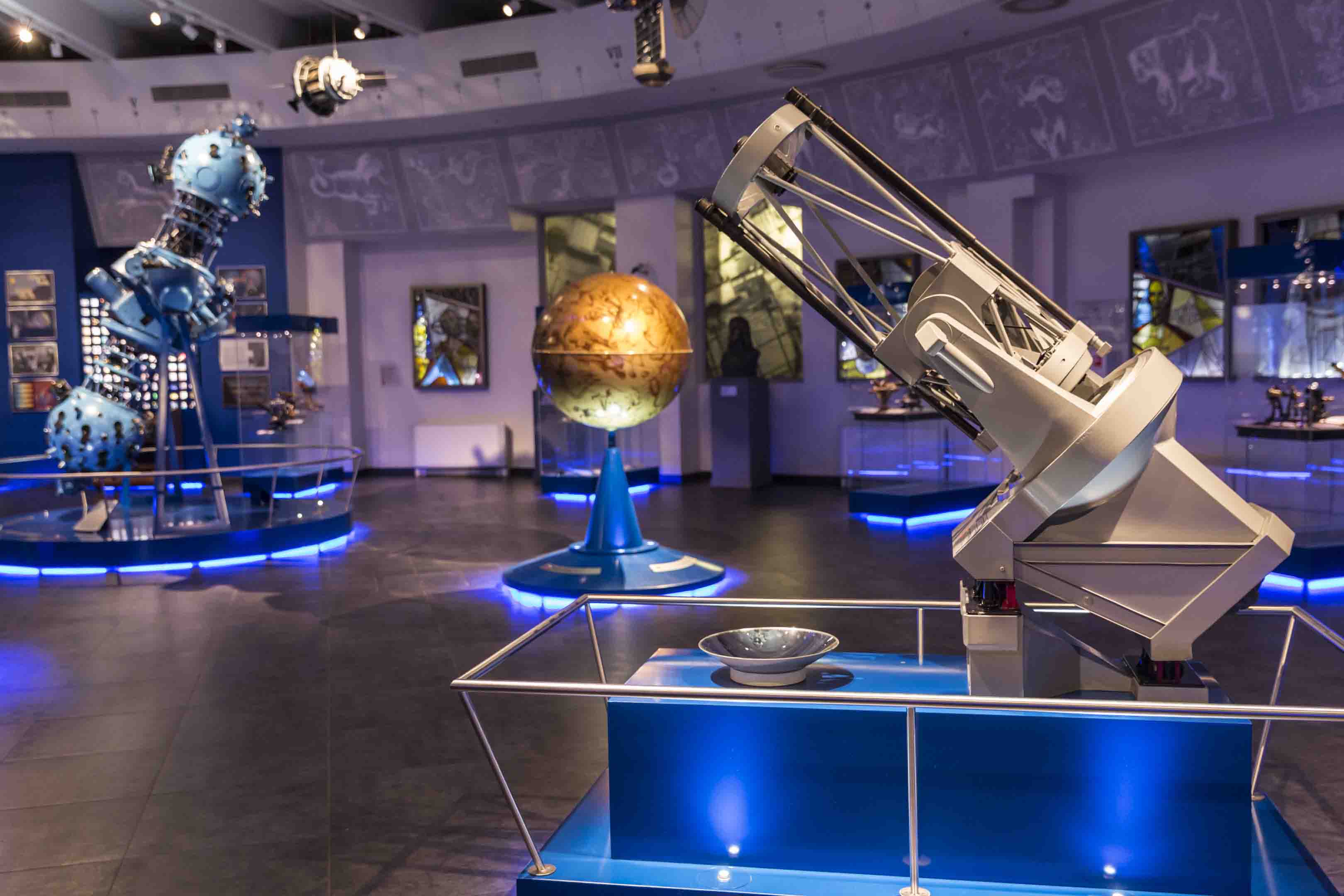 Image of various cosmology exhibits; telescope, globe and an old satellite.